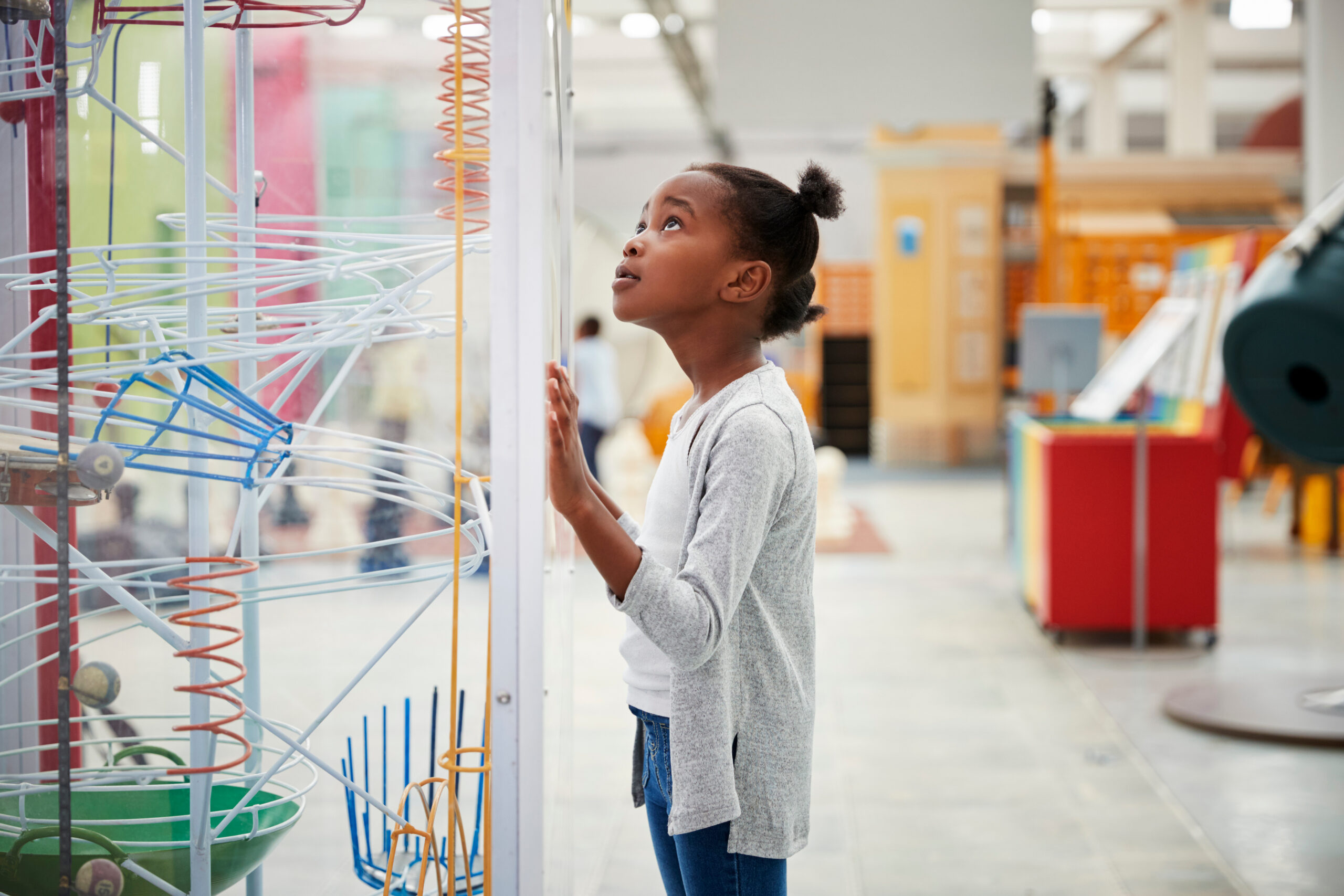 A young girl looks at a science exhibit in a glass case